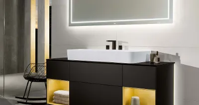 Finion Waschtischunterschrank mit beleuchteten Regalfächern Ein Finion Waschtisch mit beleuchtetem Unterschrank und Lichtspiegel in dunklem Badezimmer.