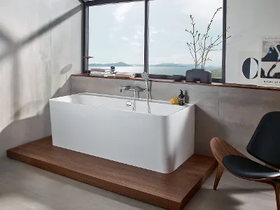 Weiße Collaro Badewanne in modernem Badezimmer mit Meerblick Modernes Badezimmer mit rechteckiger freistehender Collaro Badewanne auf einer Holzplattform und großem Fenster mit Meerblick.