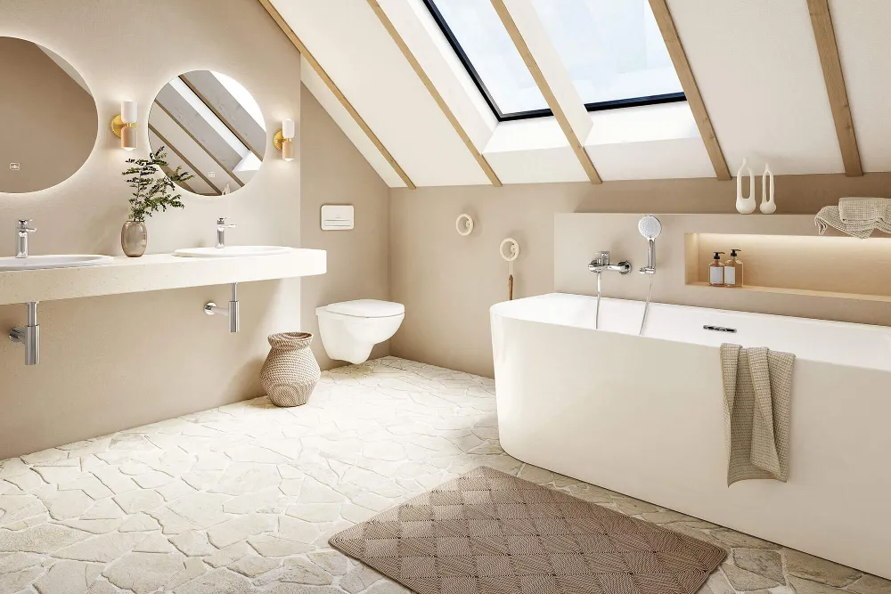 Eine Loop & Friends Badewanne in einem hellen Badezimmer mit Natursteinfliesen und Dachschräge