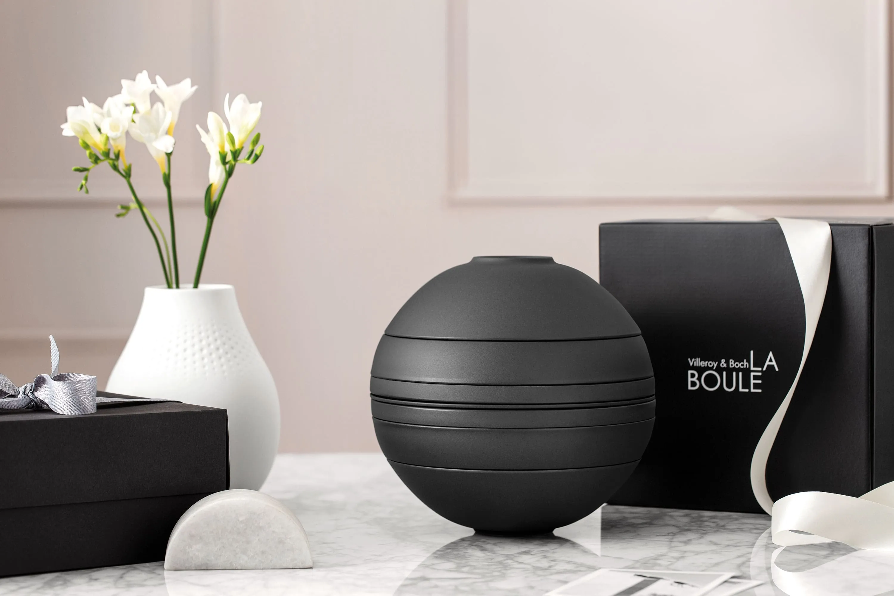 Black La Boule with gift box A black La Boule tableware set on a table with a black gift box behind it.