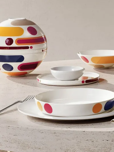 La Boule Miami on an oval stone table Oval stone table with modern colourful La Boule Miami. Shown assembled, then in individual pieces, arranged at a large window with a chair.