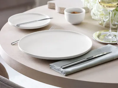 Assiettes plates Afina en relief sur une table dressée Gros plan d’une assiette plate Afina au relief discret sur une table dressée.