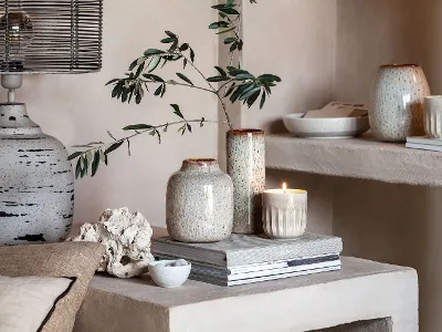 Une bougie parfumée Perlemor à côté de vases Lave Un salon avec des bougies parfumées Perlemor, des vases Lave et des livres sur une étagère.
