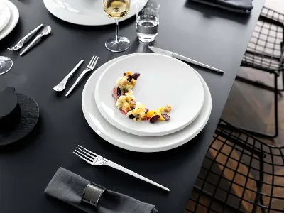 Des assiettes NewMoon avec des verres à vin Une table de salle à manger élégamment dressée avec des assiettes NewMoon et des verres à vin.