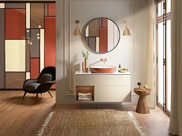 Orangenes Artis Waschbecken auf Finion Unterschrank Modernes Badezimmer mit orangefarbenem Artis Waschtisch, rundem Spiegel, beigem Finion Unterschrank und minimalistischem Dekor