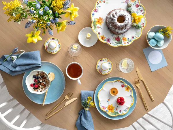 De la vaisselle Spring Awakening et Crafted Blueberry dressée pour un brunch Une table printanière décorée avec de la vaisselle Spring Awakening et Crafted, un kouglof, un plat creux rempli de flocons d’avoine avec des baies, une tasse de thé et des œufs décoratifs.