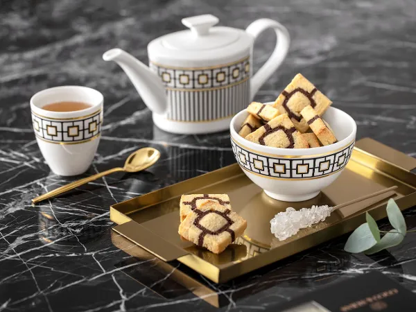Elegantes MetroChic Teeservice mit Teekanne und Tasse Elegantes MetroChic Teeservice mit Teekanne und Tasse auf goldenem Tablett, auf Marmortisch.