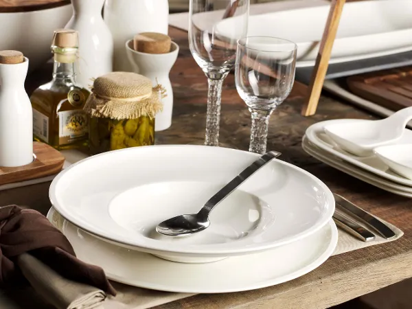 Artesano Teller mit Gewürzen Elegant gedeckter Esstisch mit weißem Artesano Geschirr, Besteck und Gläsern, dazu Olivenöl und Gewürze.
