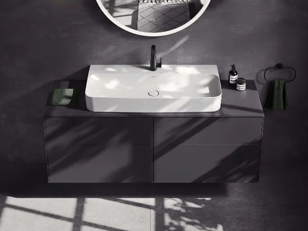 Badezimmer im All Black Stil mit Dachschrägenbad All Black-Badezimmer mit verglaster Dusche, schwarzes 'Antao'-WC, wandmontiertem 'Antao'-Waschtisch mit 'Loop & Friends'-Aufsatzwaschbecken, Spiegel und Fenster, das Tageslicht hereinlässt.