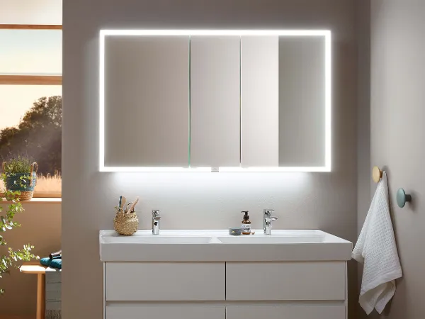 My View Now Spiegelschrank mit eingeschaltetem Licht Ein moderner Badezimmerwaschtisch mit hinterleuchtetem Spiegelschrank und übersichtlichem Zubehör