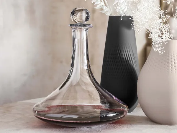 Vinobile Weinkaraffe mit Manufacture Vasen Eine elegante Vinobile Weinkaraffe aus Glas und Manufacture Vasen mit weißen Blumen.