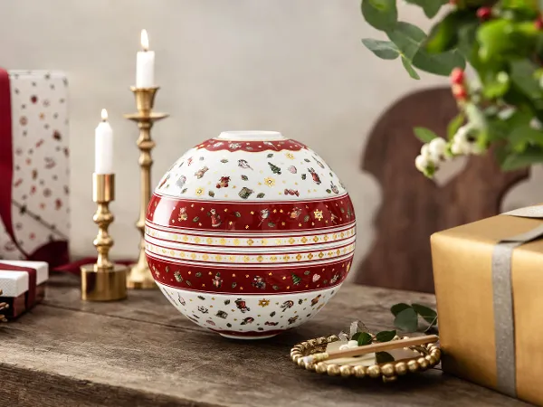 Toy's Delight La Boule auf einem Holztisch Toy's Delight La Boule auf einem Holztisch, umgeben von Kerzen, Geschenken und einem Tannenzapfen.