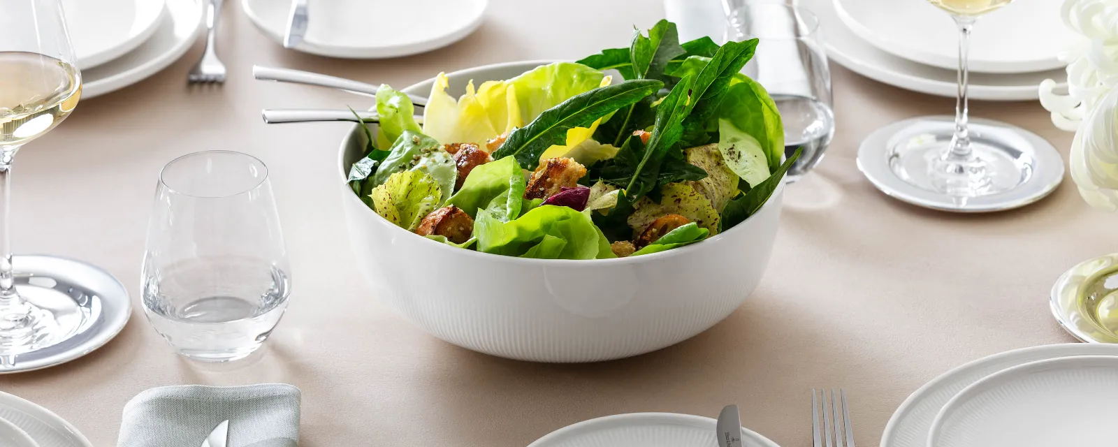 Weiße Afina Schüssel mit Salat Große Afina Servierschüssel von Villeroy & Boch, gefüllt mit Salat, auf einem gedeckten Tisch.