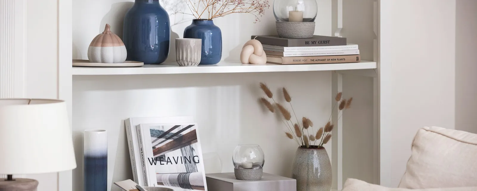 Blaue Vase Laven auf einem Bücherregal Ein Wohnzimmer mit Bücherregalen und blauen Lave Vasen von like. by Villeroy & Boch.